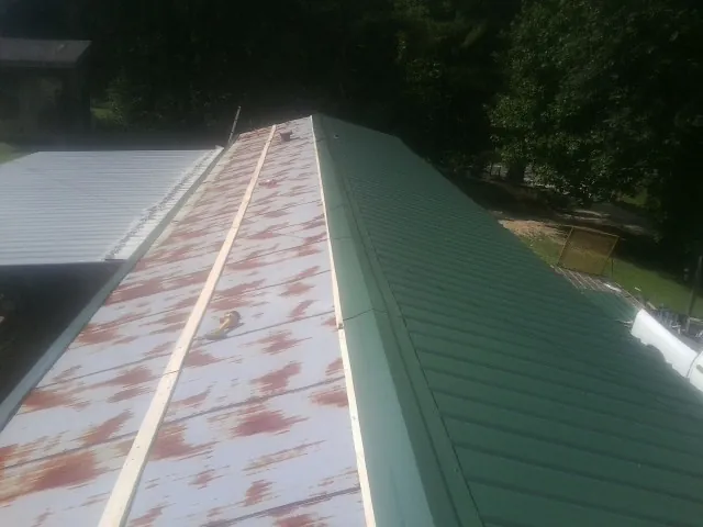 Old rusted panels beside newly installed green metal roofing — Wind Damage Roof Repair by Roofing Brothers in Bonner Springs