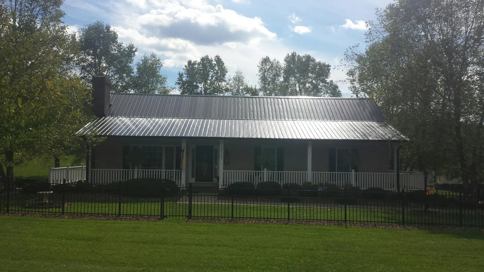 Gray metal roof on a brick ranch with a full width front porch — Gutter Guard Installation work by our crew in Bonner Springs