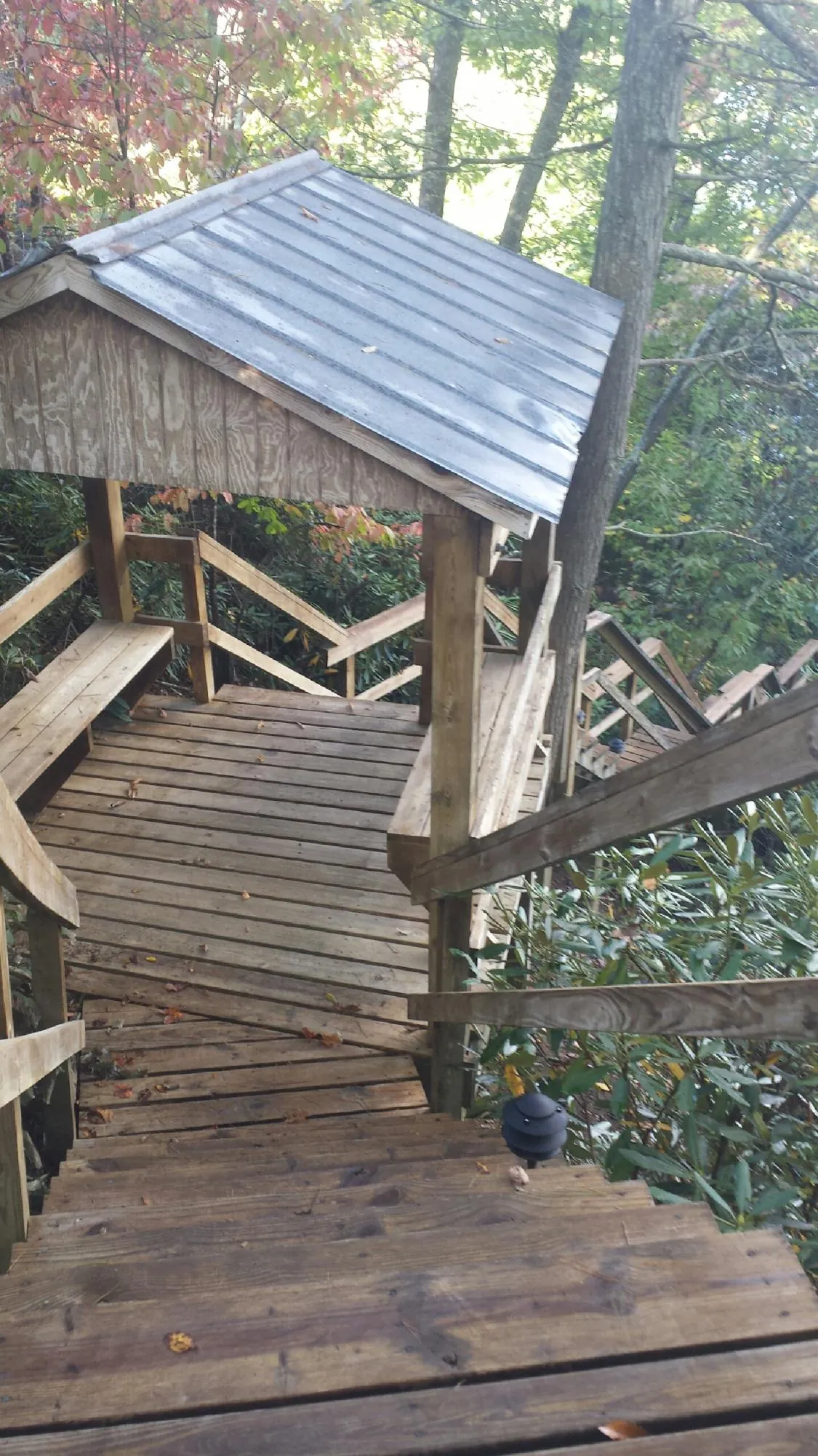Metal roofed shelter over wooden steps on a wooded walkway — Skylight Repair & Installation work by our crew in Bonner Springs