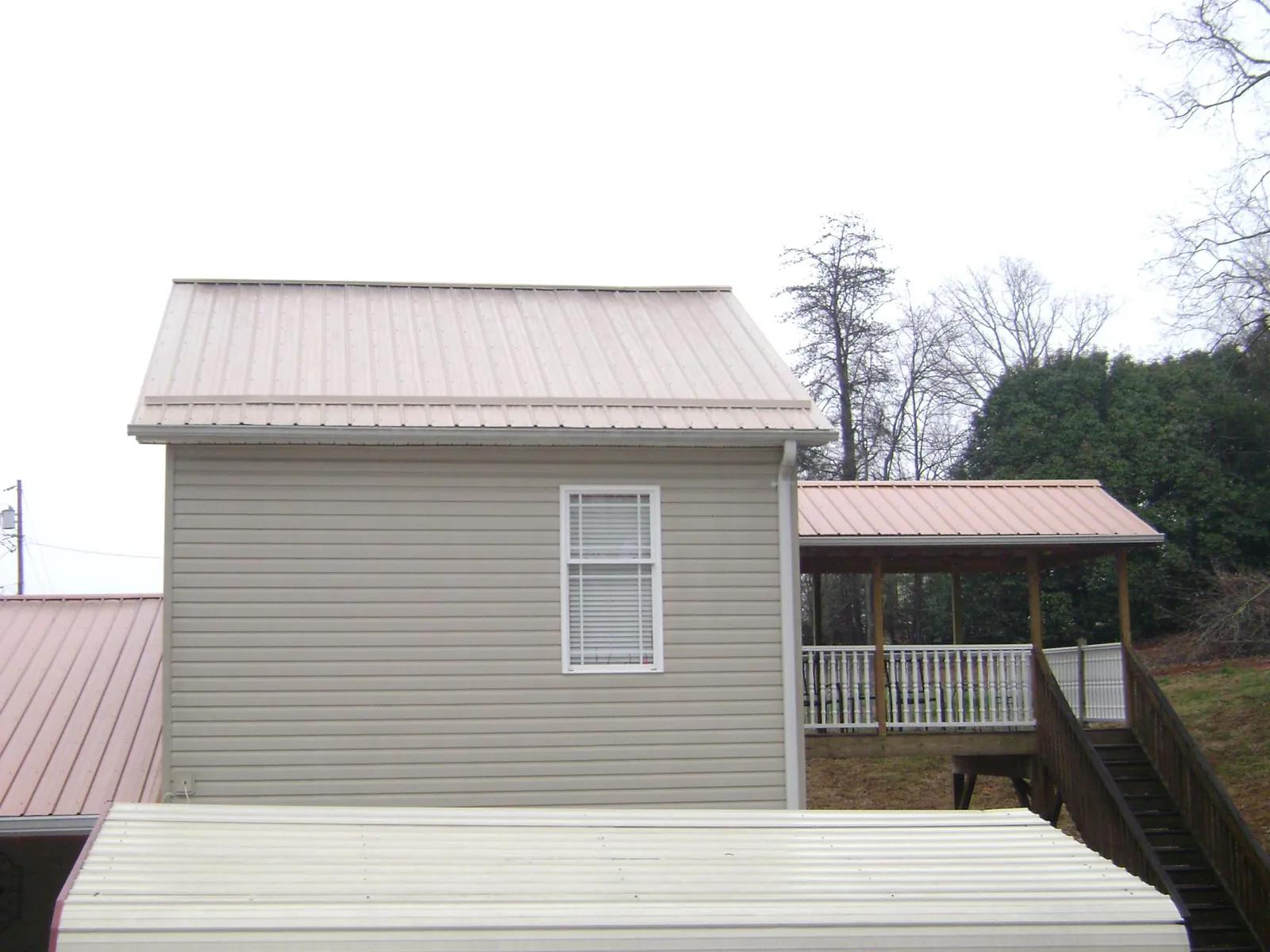 Tan metal roofs on a two story addition and attached porch, from a Roof Replacement job in Bonner Springs
