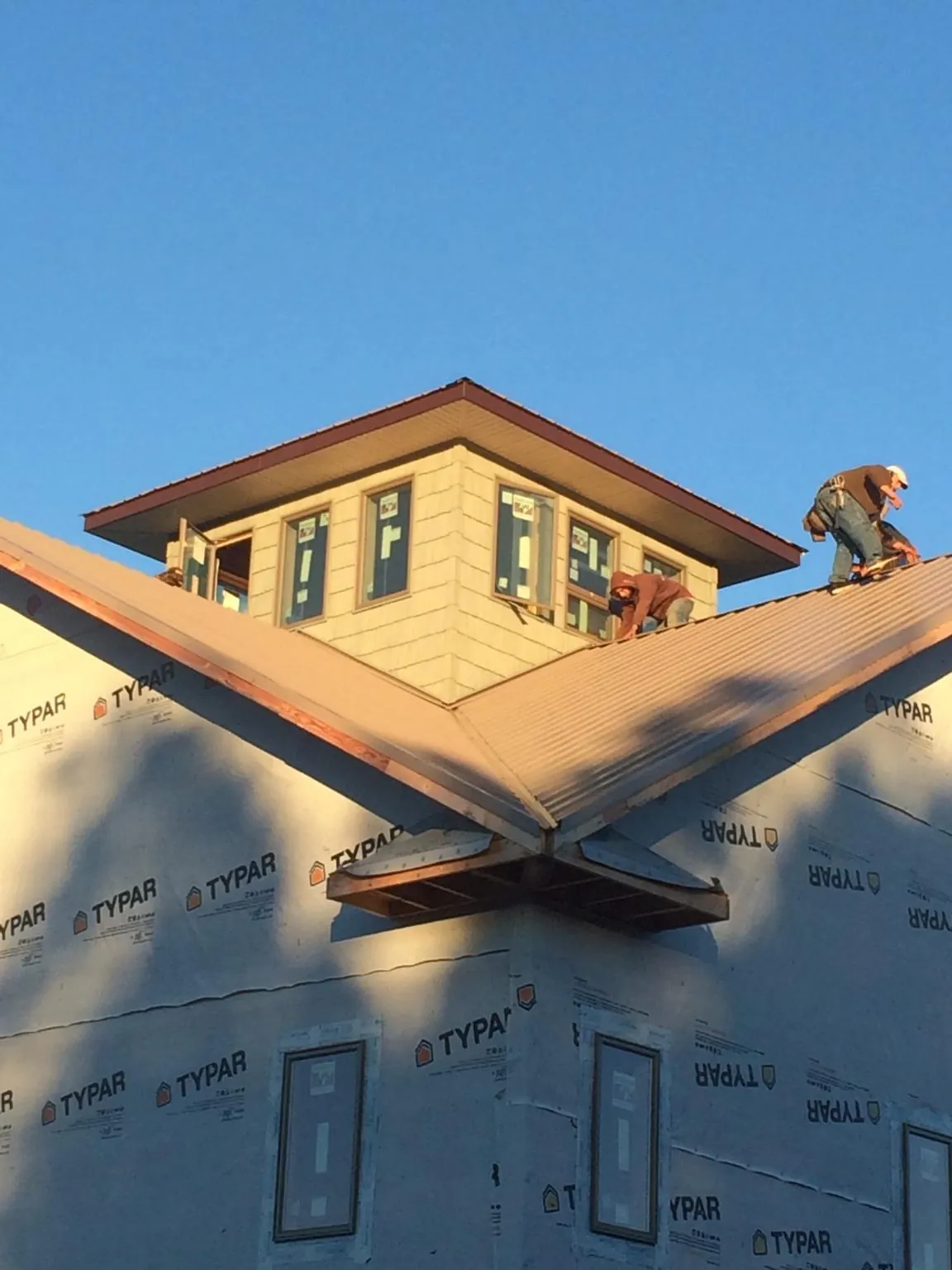 Roofers working around a rooftop cupola on a new metal roof at sunset — Roof Waterproofing in Bonner Springs by Roofing Brothers